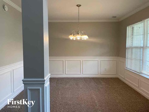 a dining room with white wainscoting and a chandelier
