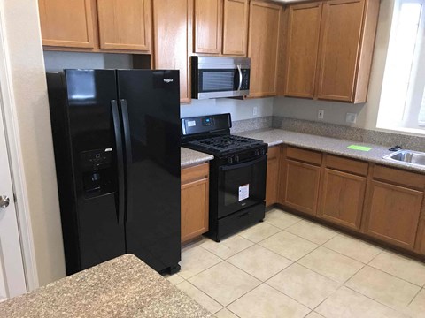 A black refrigerator and black stove in a kitchen.