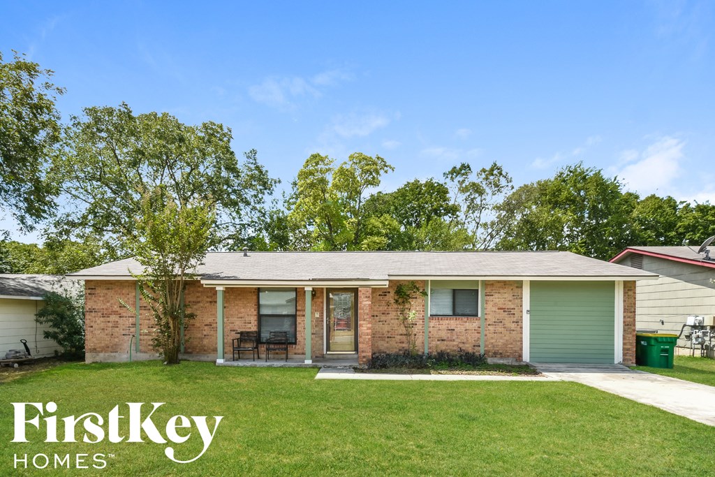 front view of a brick house with green grass and trees
