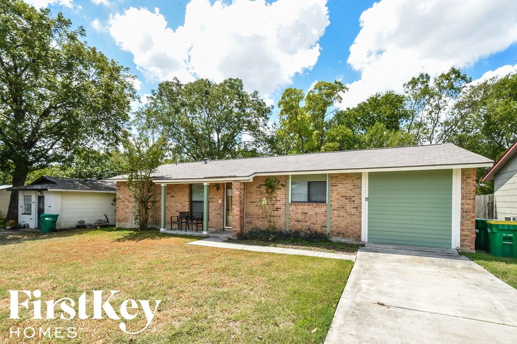 a small brick house with a lawn and a green garage door