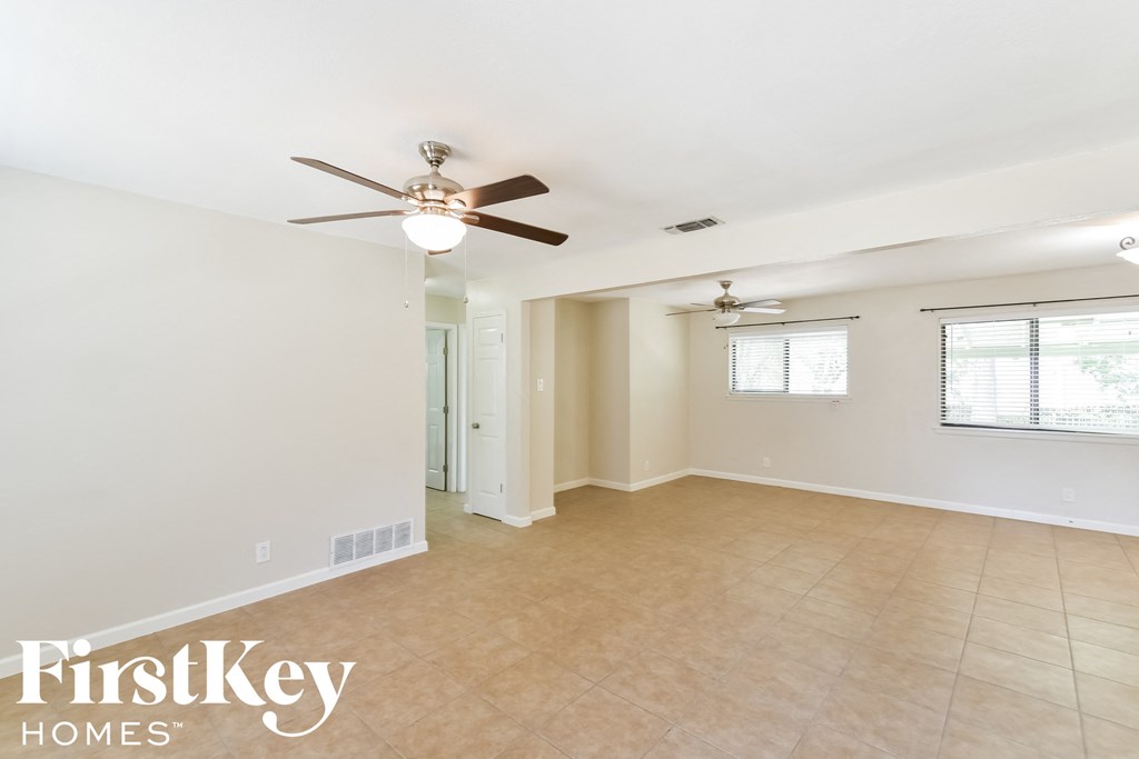 an empty living room with a ceiling fan and a tiled floor