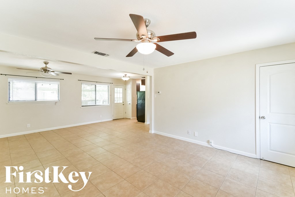 an empty living room with a ceiling fan and a tiled floor