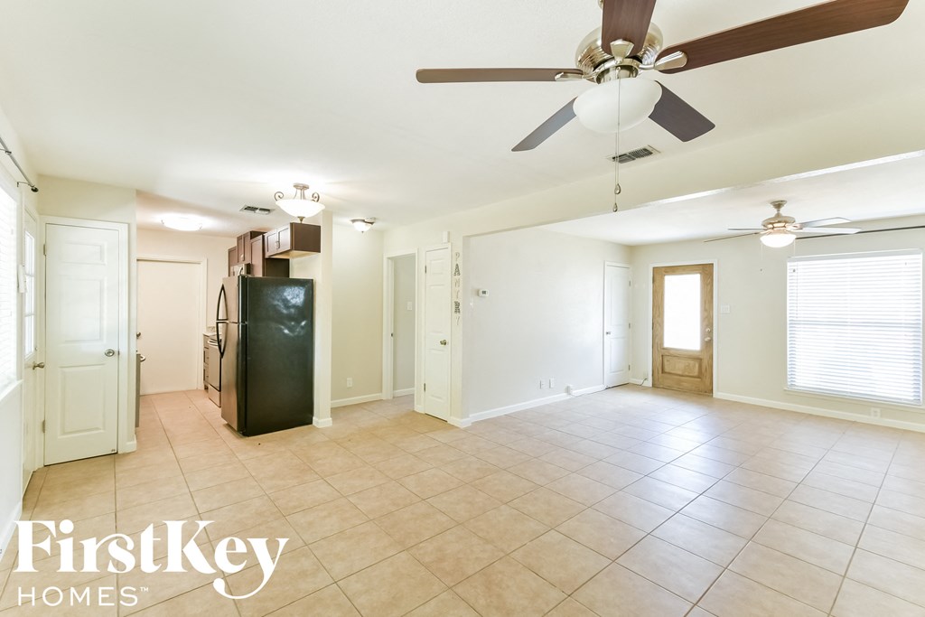 an empty living room with a ceiling fan and a tile floor