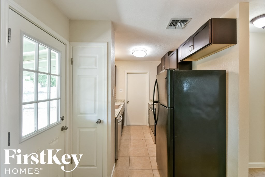 a kitchen with a black refrigerator and a window