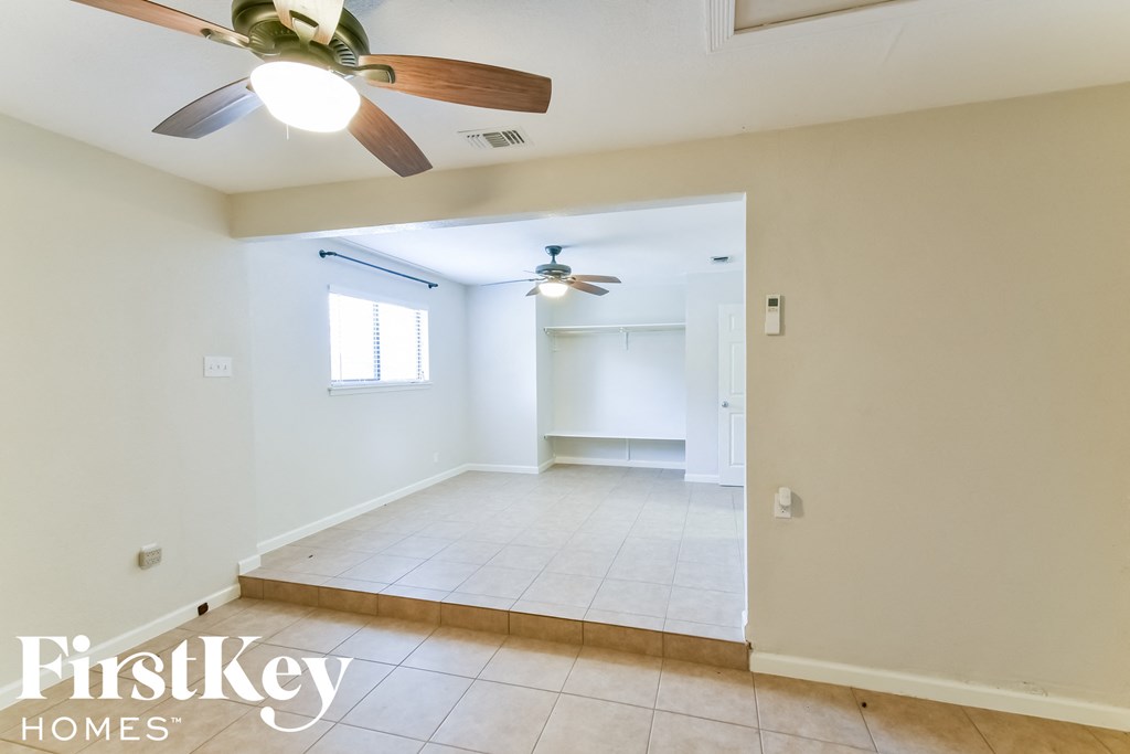 an empty living room with a ceiling fan and a tiled floor