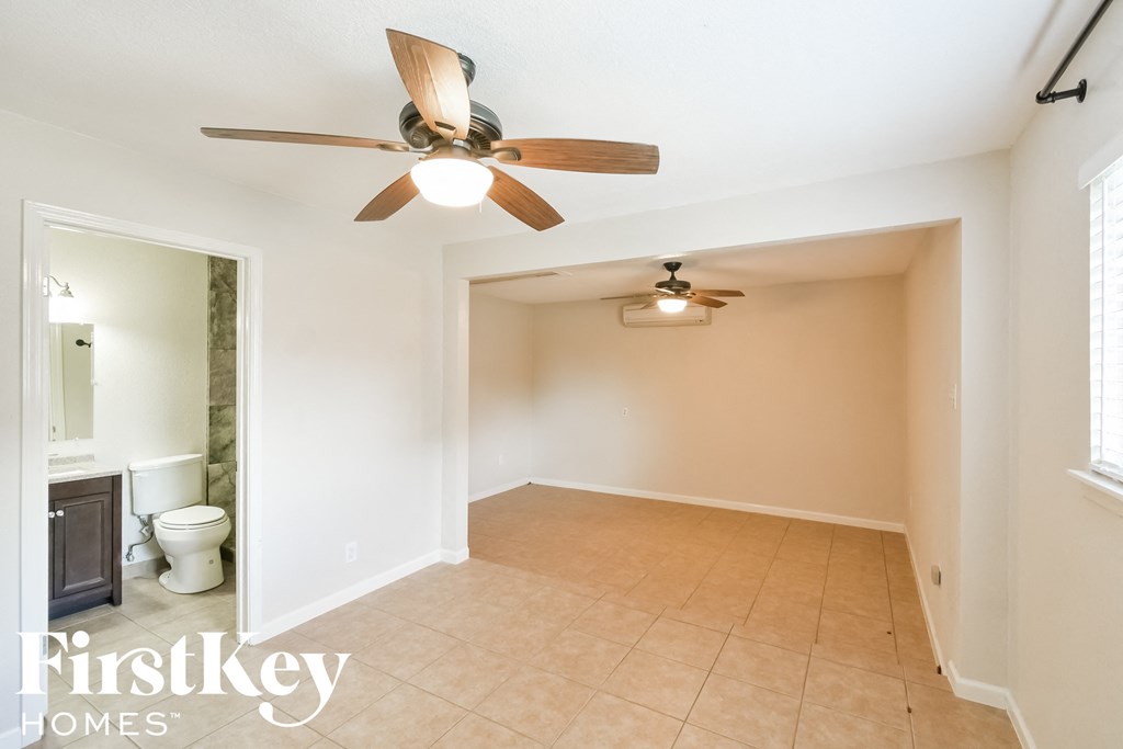 an empty living room with a ceiling fan and a bathroom