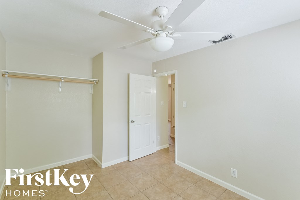 a bedroom with a ceiling fan and a door to a closet