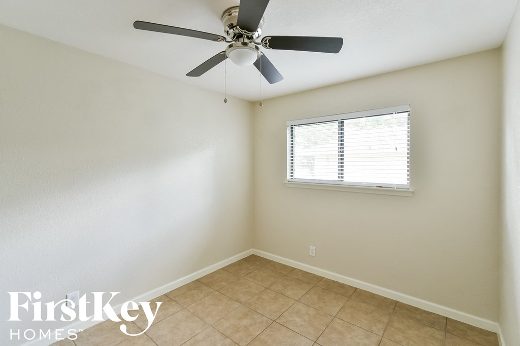 an empty room with a ceiling fan and a window