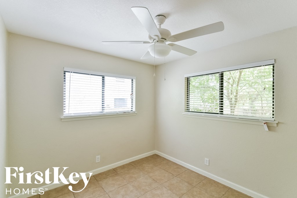 a bedroom with a ceiling fan and two windows