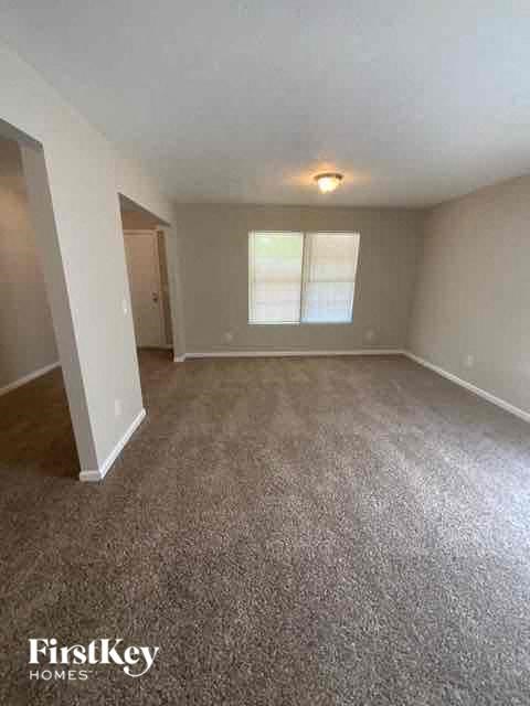 an empty living room with carpet and a window