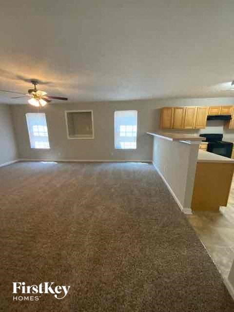 an empty living room and kitchen with a ceiling fan