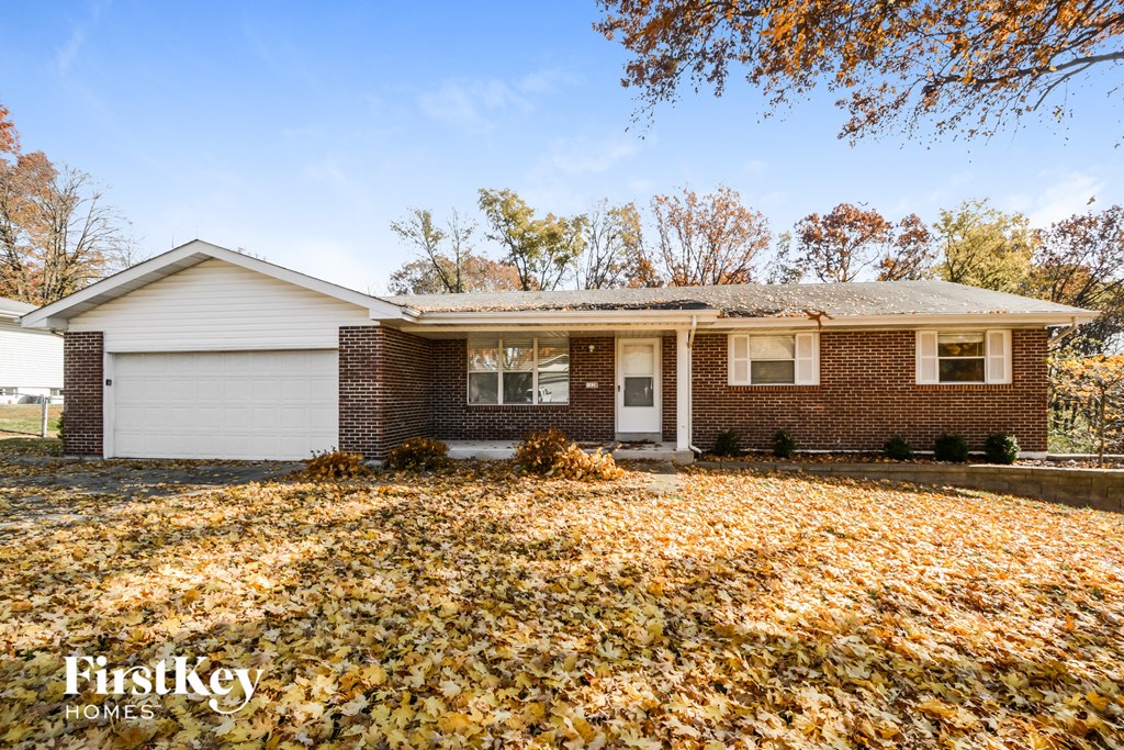 a brick house in the fall with leaves on the ground