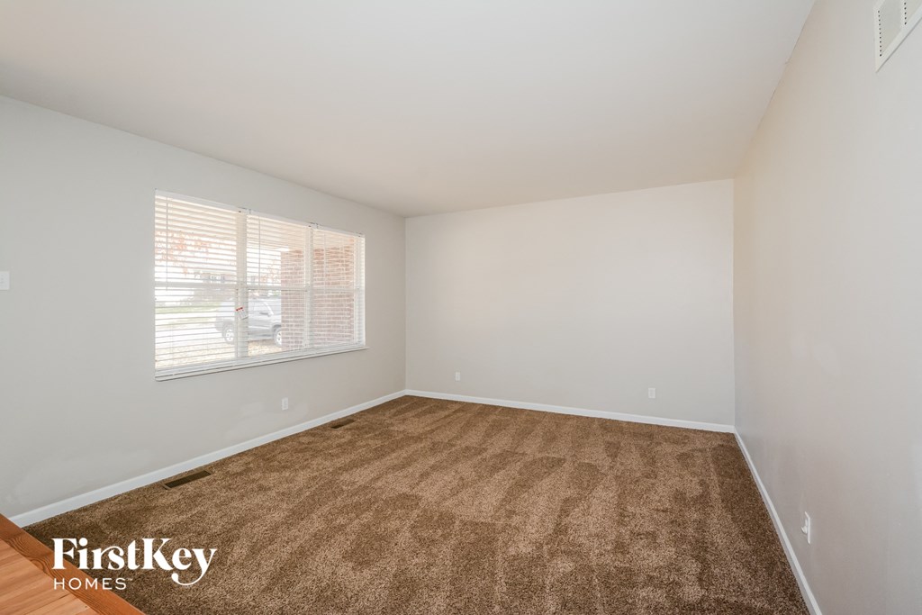a spacious living room with carpet and a large window