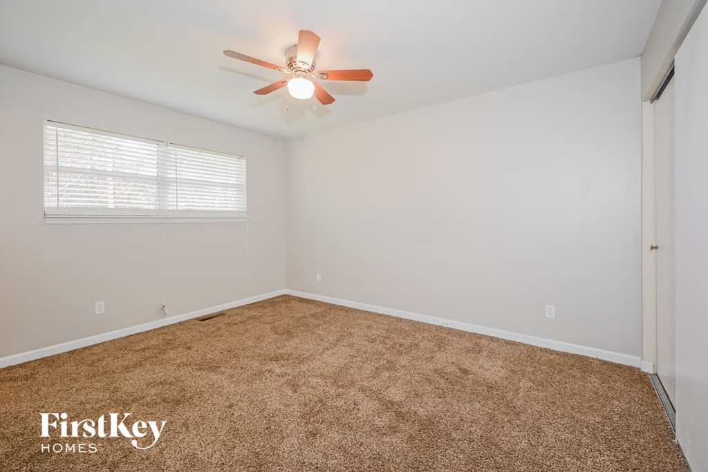 a bedroom with a carpeted floor and a ceiling fan