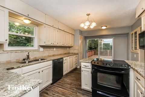 A kitchen with a black oven and wooden floors.