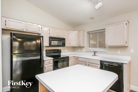 a white kitchen with black appliances and white counter tops