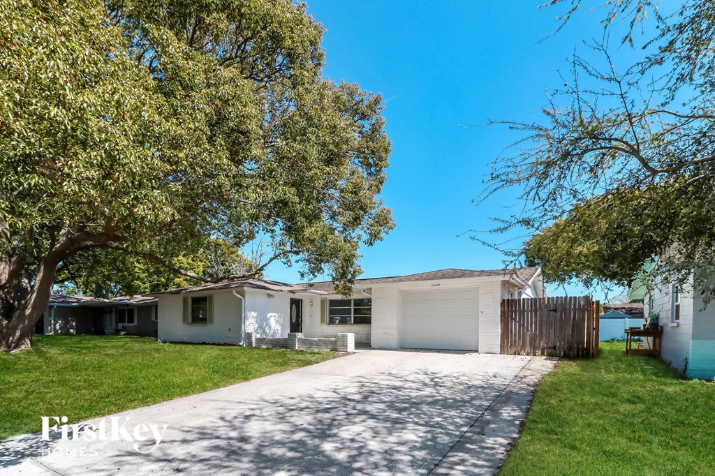 a white house with a driveway and a tree