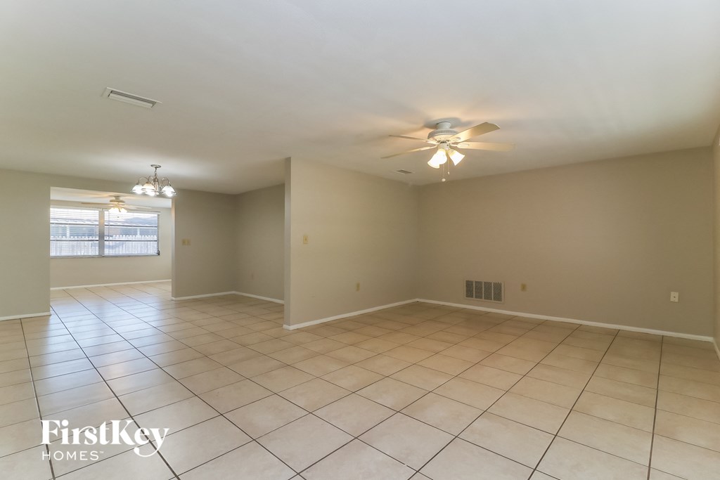 a spacious living room with tile flooring and a ceiling fan