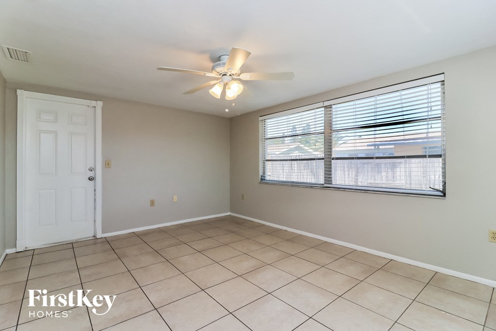an empty living room with a large window and a ceiling fan