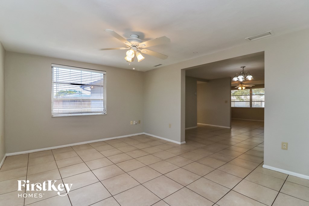 an empty living room with a ceiling fan and tiled floor