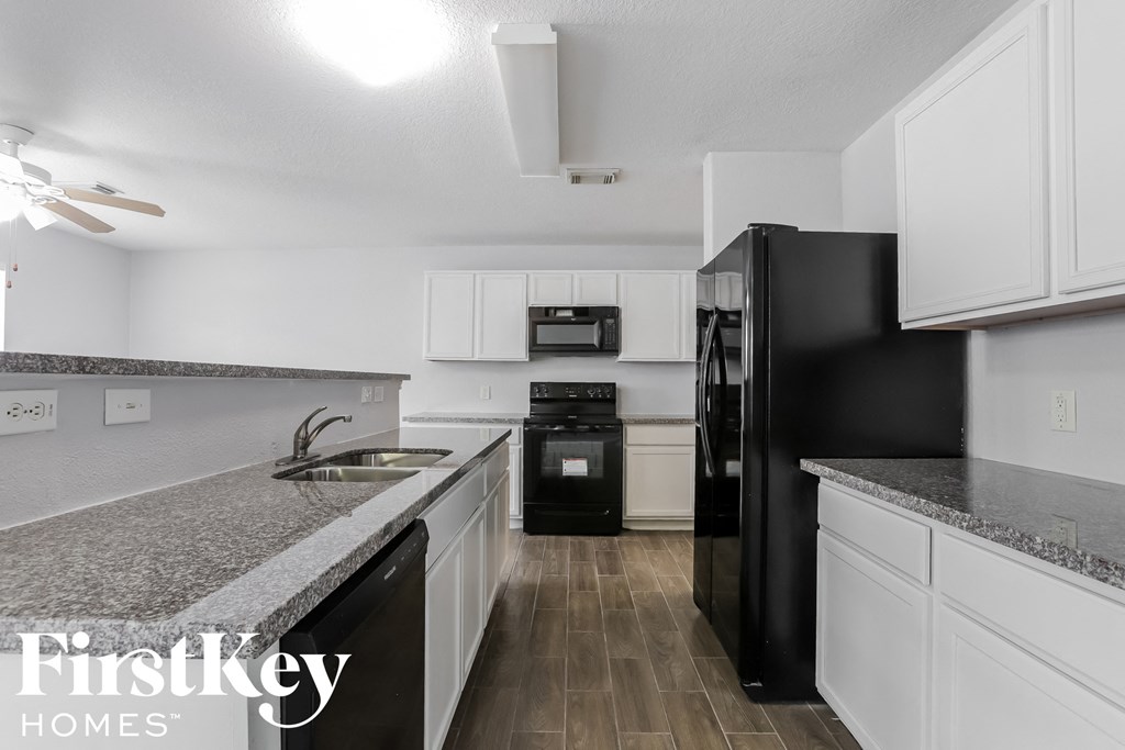 A kitchen with black appliances and white cabinets.