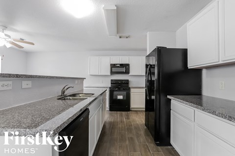 A kitchen with black appliances and white cabinets.