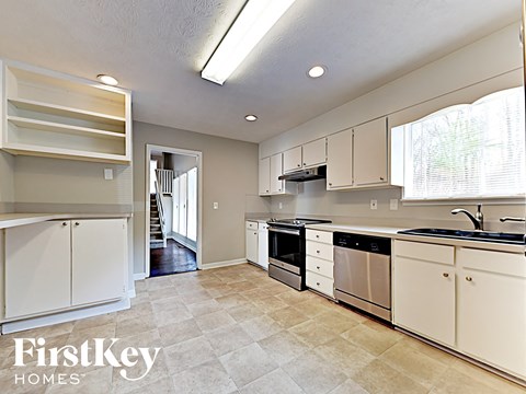 A kitchen with white cabinets and appliances, and a tiled floor.