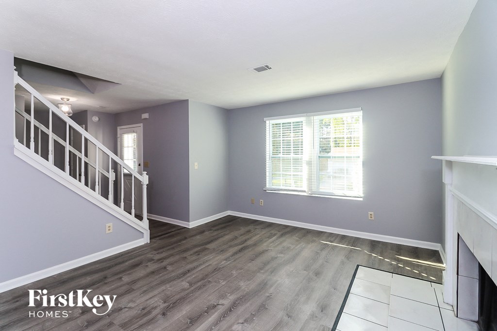 an empty living room with grey walls and a white staircase
