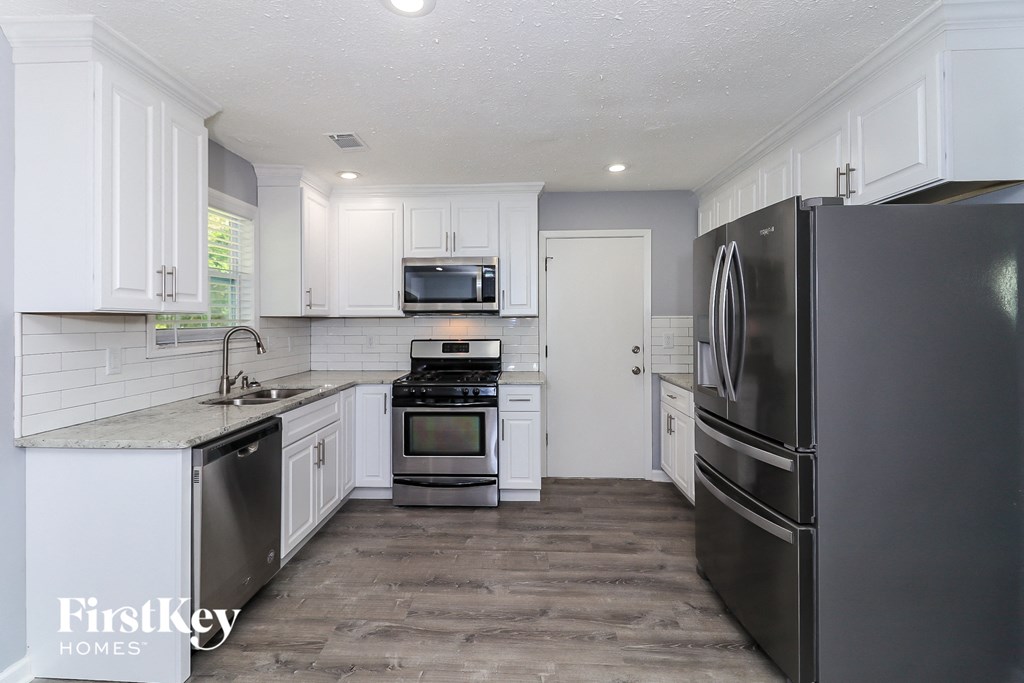 a white kitchen with stainless steel appliances and white cabinets