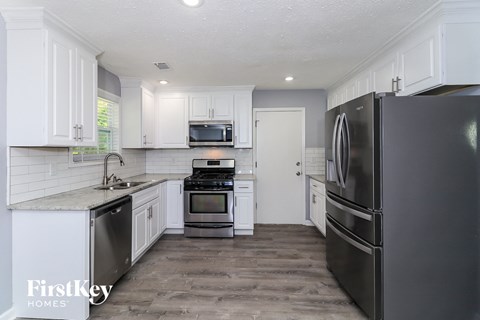 a white kitchen with stainless steel appliances and white cabinets