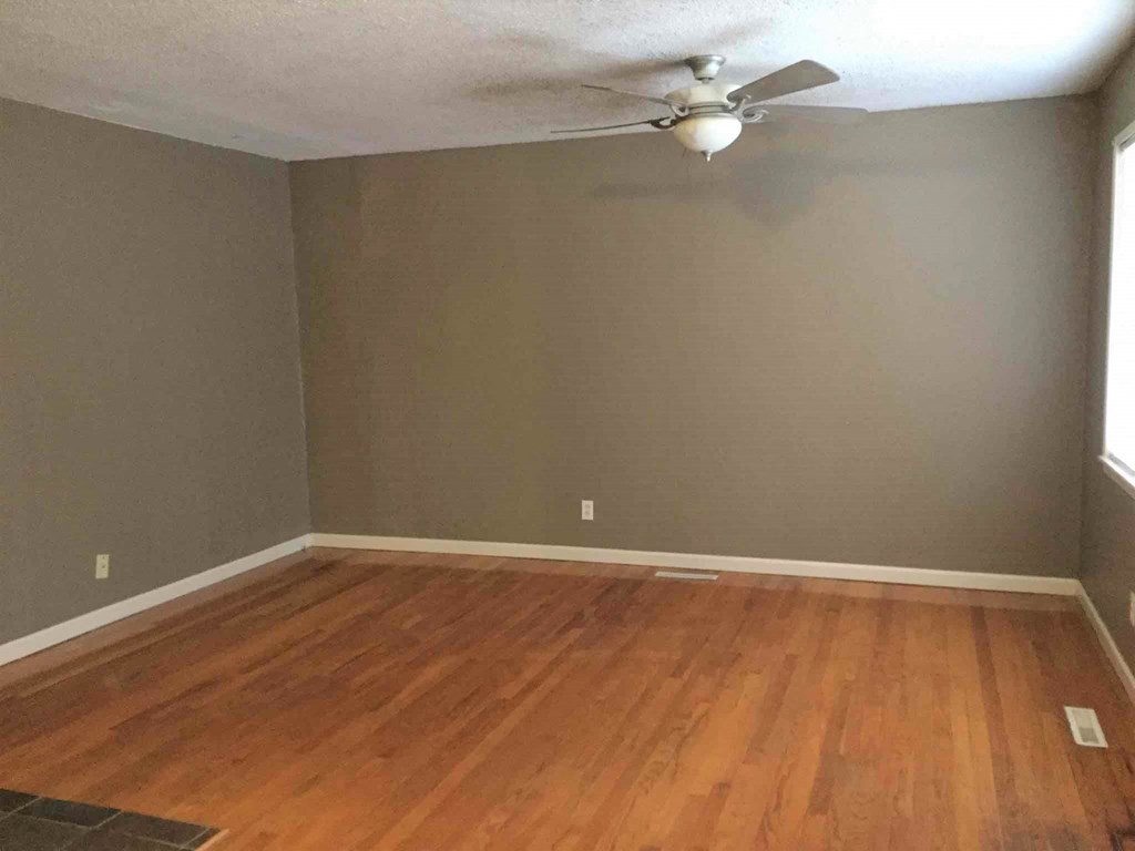 A room with a ceiling fan and wooden flooring.