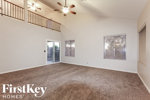 the spacious living room with carpeting and a ceiling fan