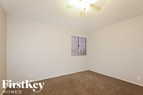 a bedroom with white walls and carpet and a window