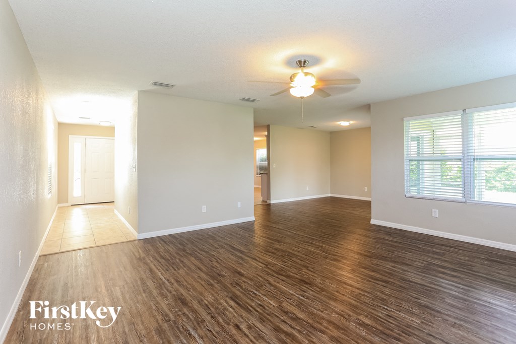 an empty living room with wood flooring and a ceiling fan