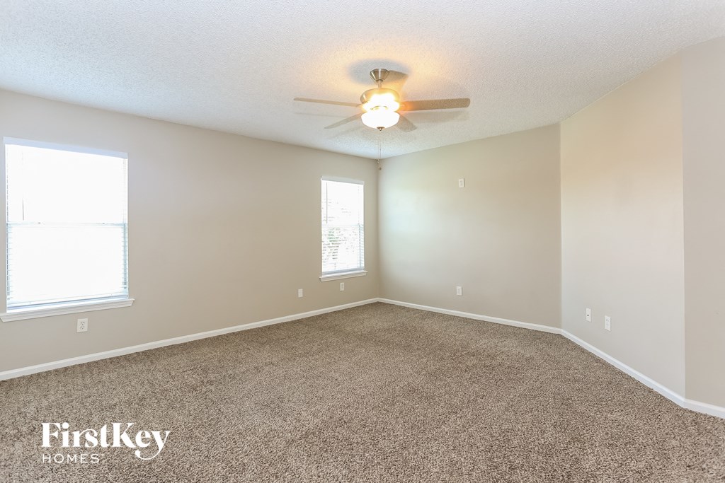 the spacious living room with carpeting and a ceiling fan