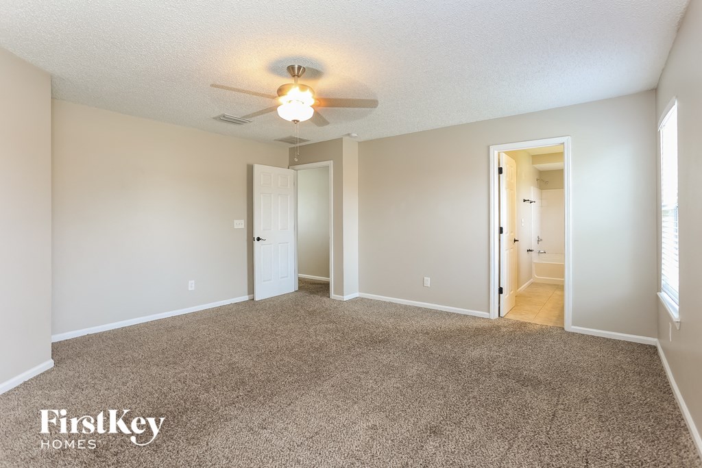 a spacious living room with carpeting and a ceiling fan
