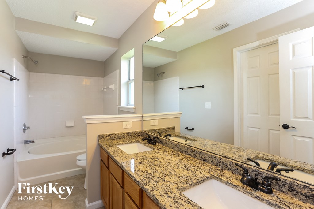 the master bathroom has a large vanity with dual sinks and a large mirror