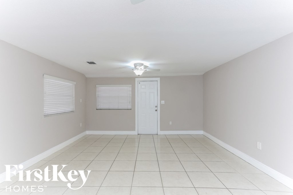 a empty living room with a white tile floor and a white door