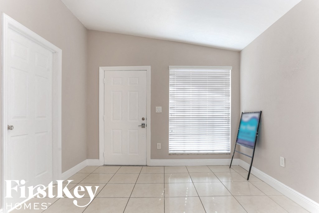 a room with a tile floor and a white door and a window
