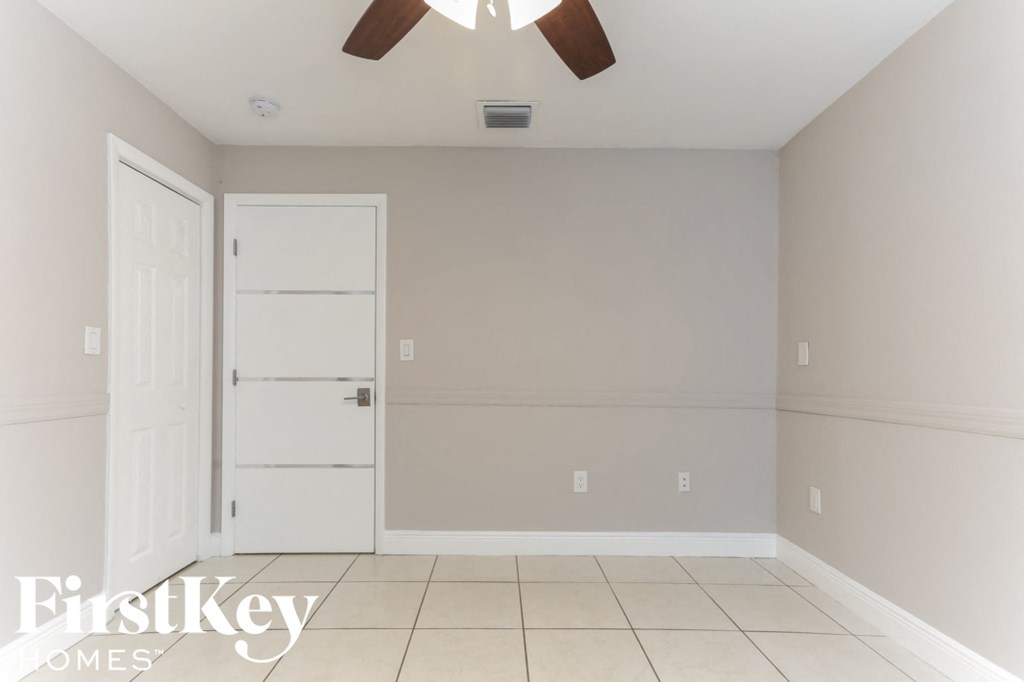a empty dining room with a ceiling fan and a white door