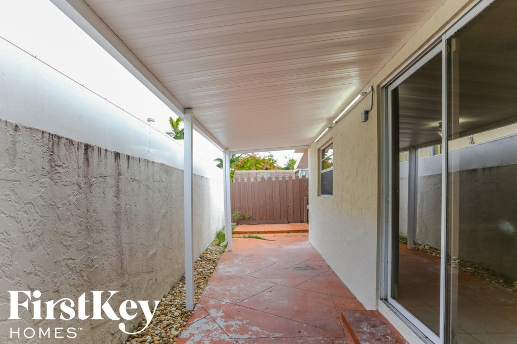 a covered walkway leading to a patio with glass doors