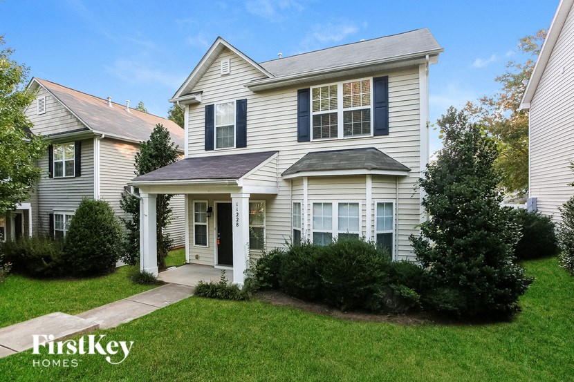 a white house with black shutters and a lawn and trees