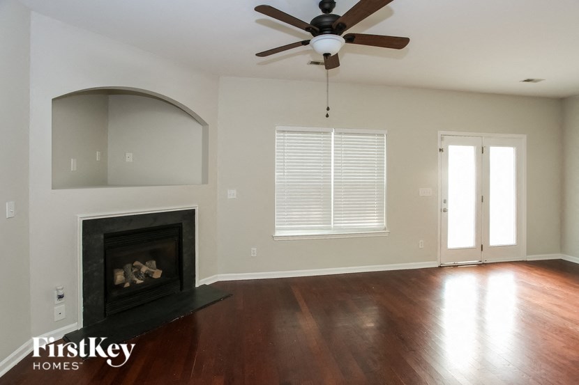 an empty living room with a fireplace and a ceiling fan