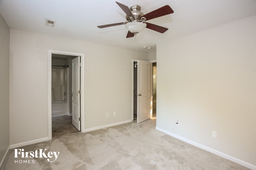 a living room with a ceiling fan and a hallway with a closet