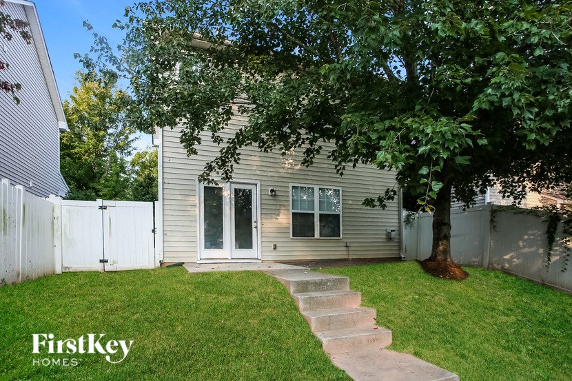 a backyard with a tree and a white house