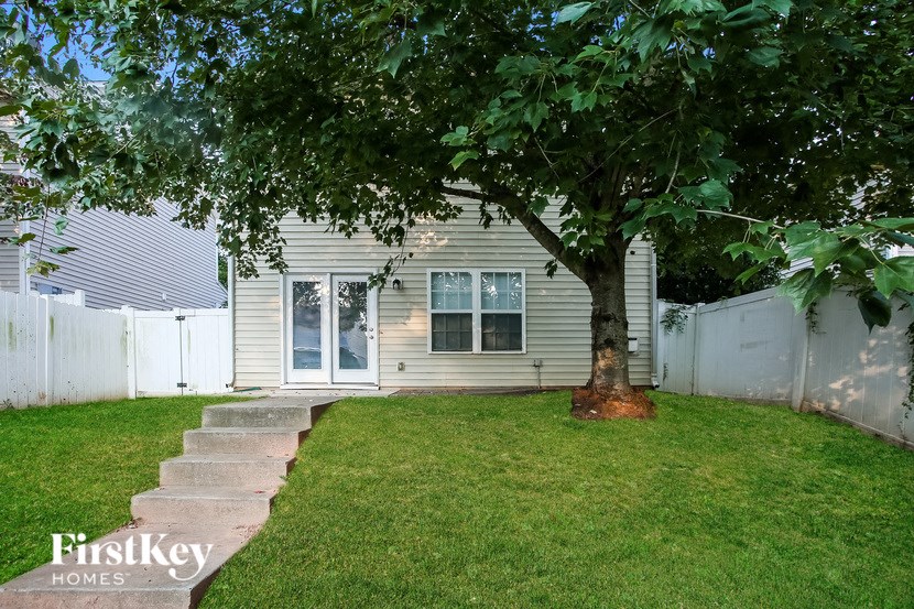 a backyard with a tree and a white house