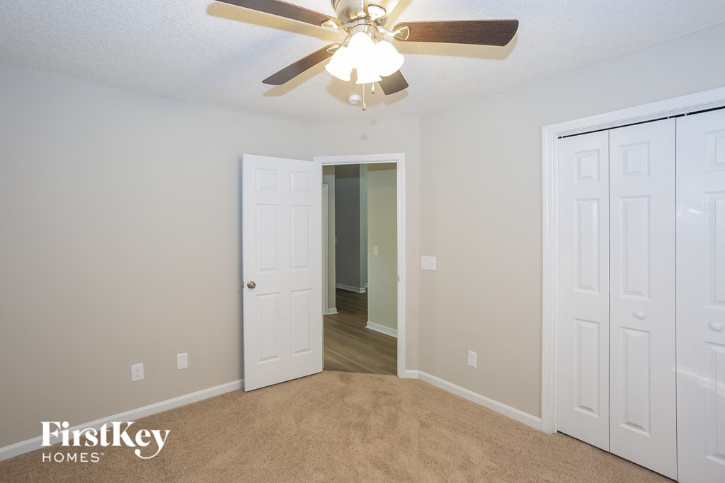 a bedroom with a ceiling fan and a door to a closet