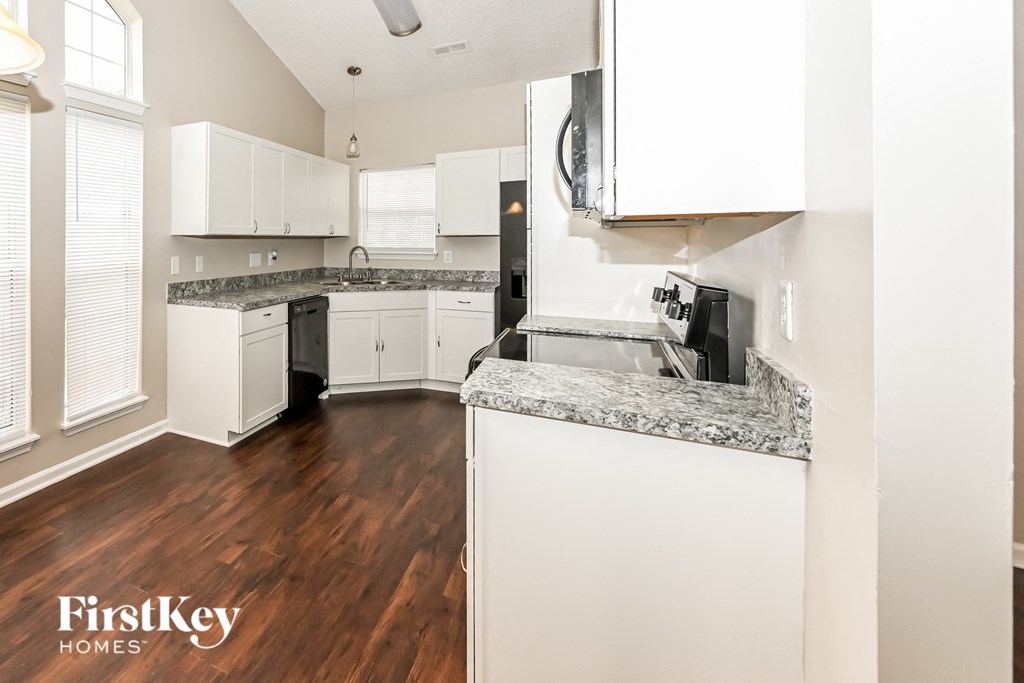 a renovated kitchen with white cabinets and granite counter tops