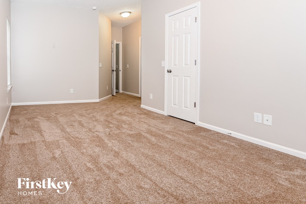 a bedroom with a carpeted floor and a door to a closet