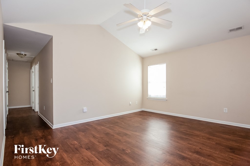 the spacious living room with wood flooring and a ceiling fan